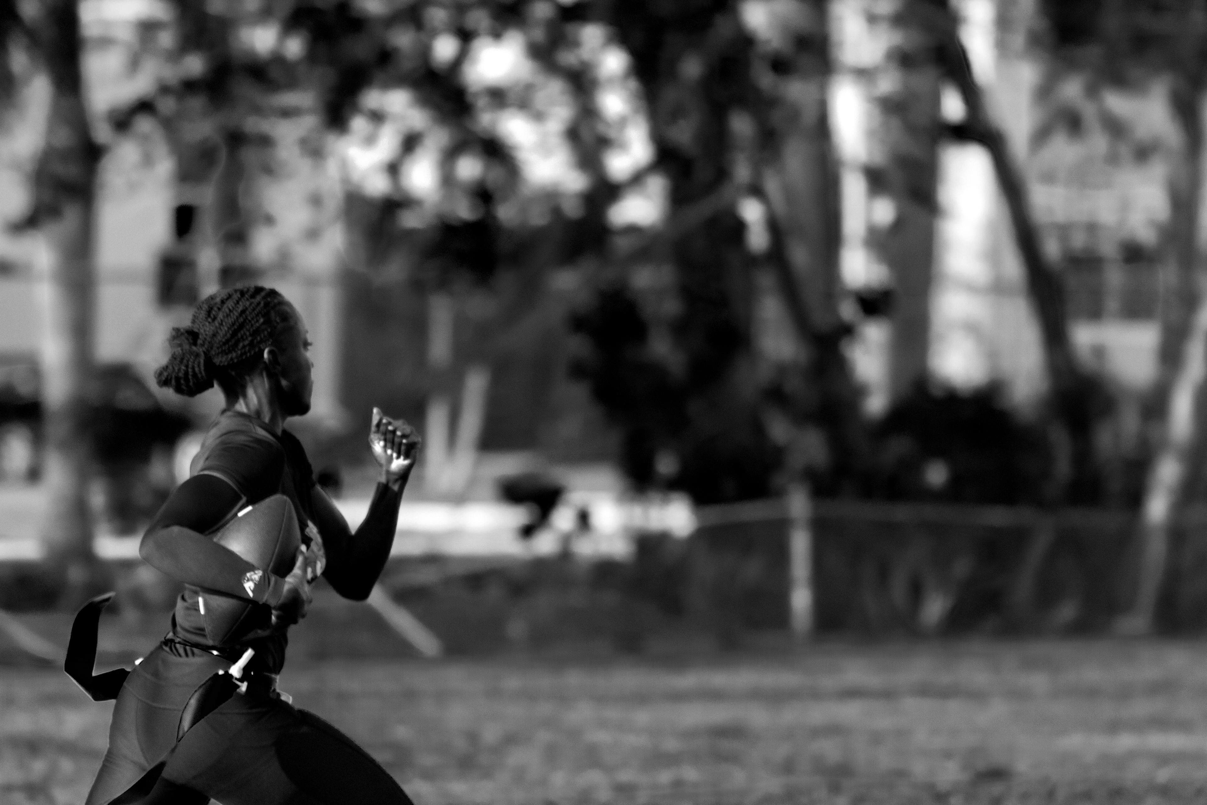 Editorial portrait of a woman athlete running with a football